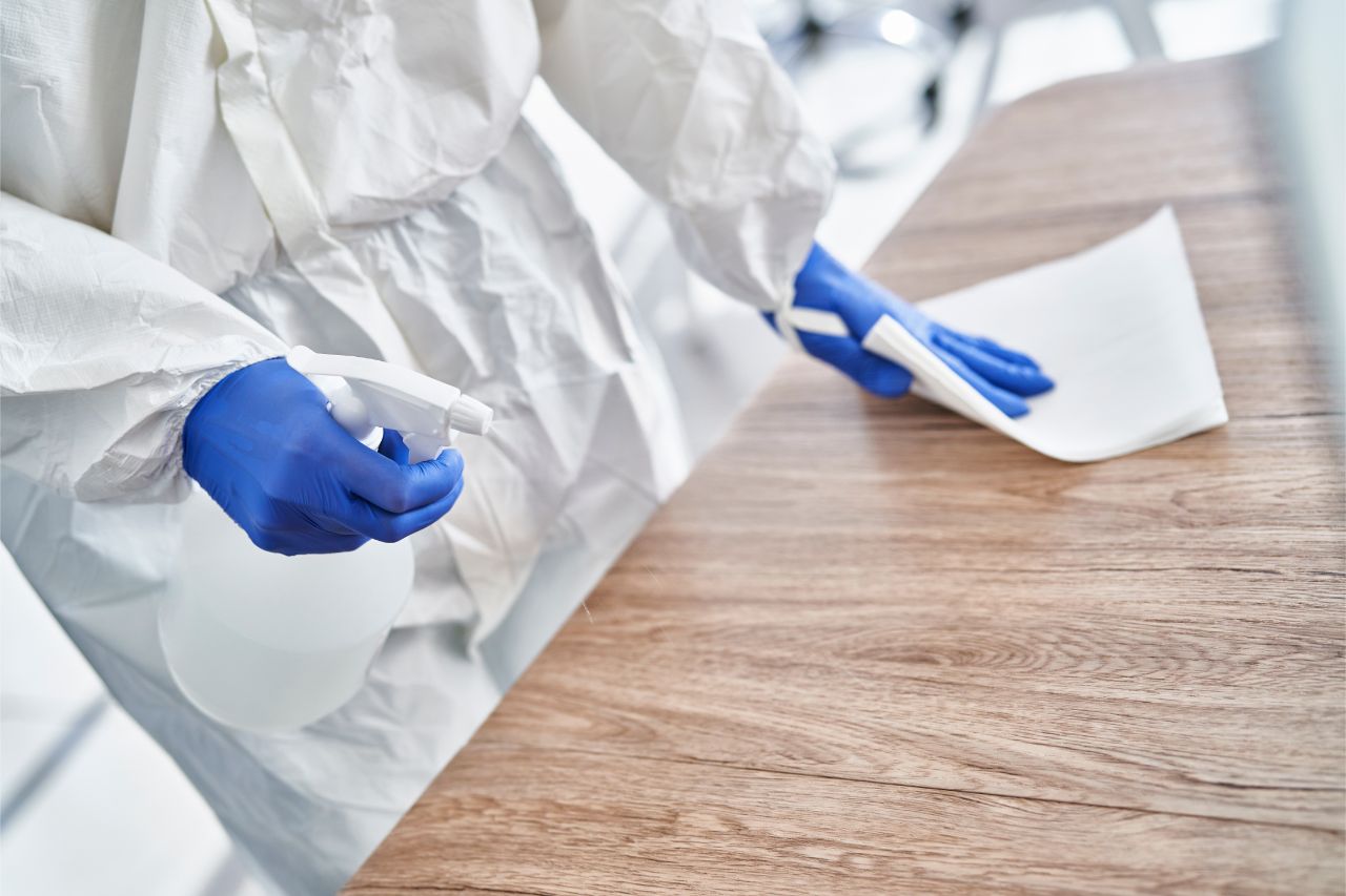 Person in PPE disinfecting a table