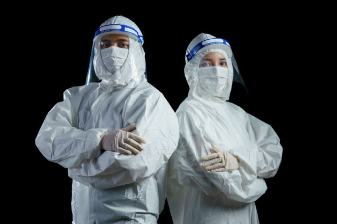 Man and woman healthcare worker in coveralls, face masks, and face shields