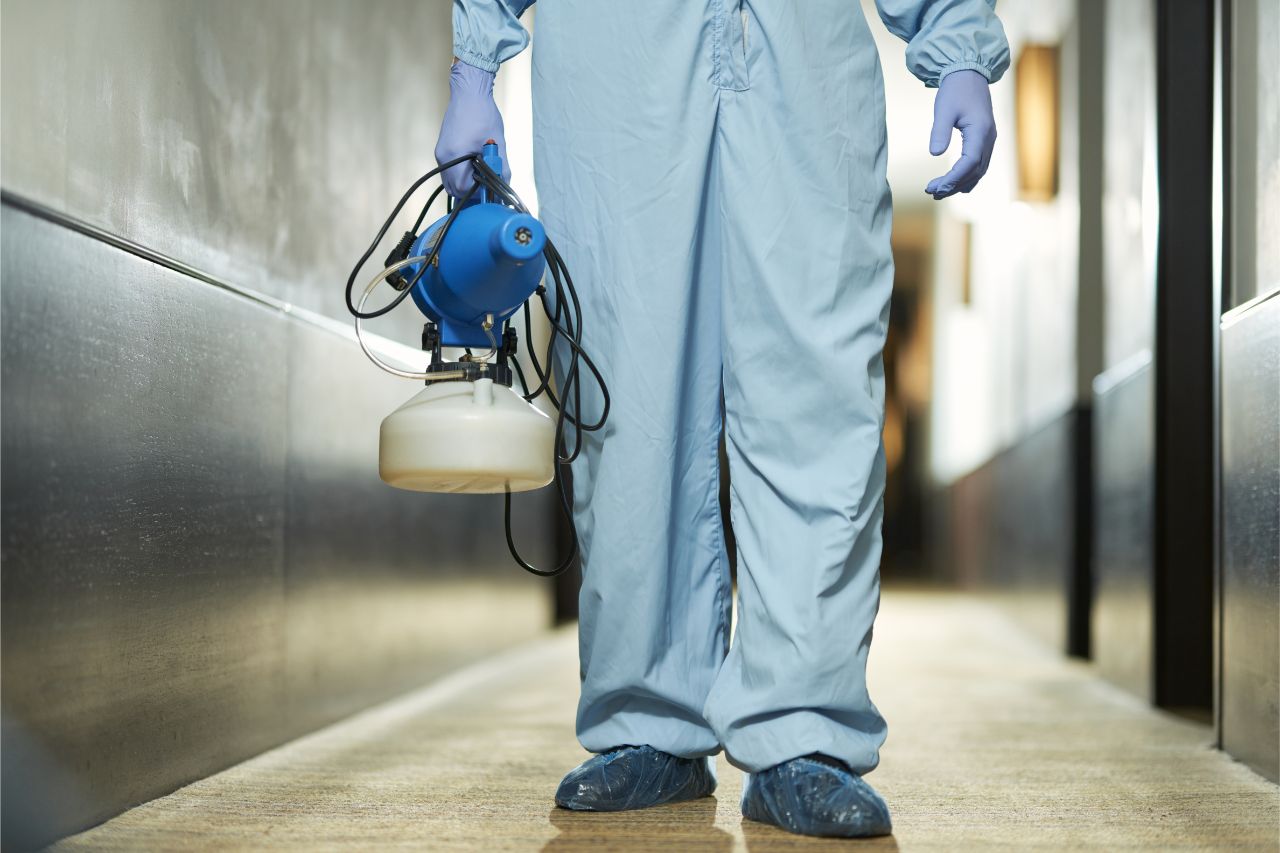 Employee in PPE disinfecting the workplace